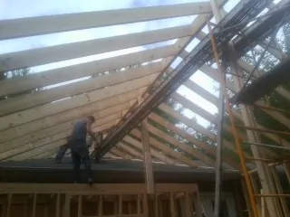 Rafters going up over a new addition with a worker on the wall in Bellaire